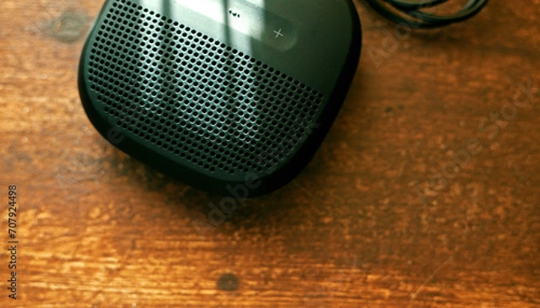 Obraz closeup photo of a black wireless speaker on a wooden table