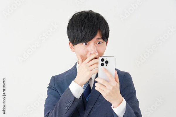 Fototapeta スマートフォンを見て驚くビジネスマン　白背景