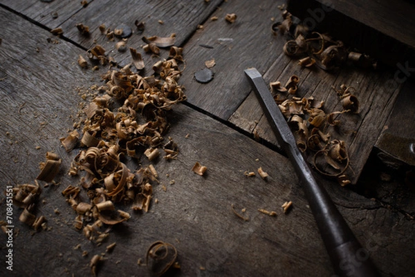 Fototapeta A carpenter carves wood with a chicel



