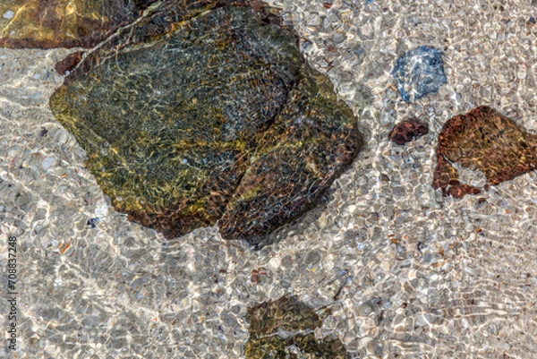 Fototapeta looking down view of stone on the beach with water waves slow drifting wallpaper background
