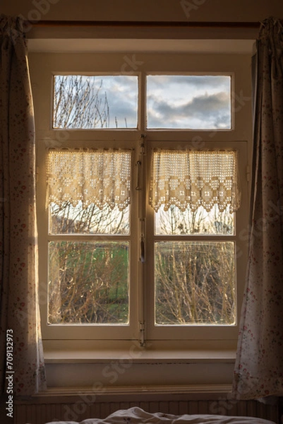 Fototapeta View of the natural countryside through an old-fashioned window with net curtains on the sides.