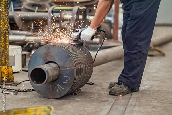 Fototapeta Worker using an angle grinder, making a screw conveyor