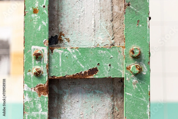 Fototapeta Detail of a pillar with a green steel frame affected by rust in an old abandoned factory.