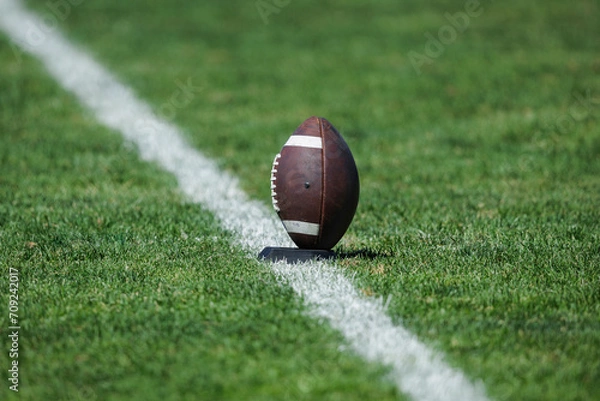 Obraz American football resting on a kicking  tee stand ready to be kicked to start off a football game. The football game is ready to begin. Time for Kickoff