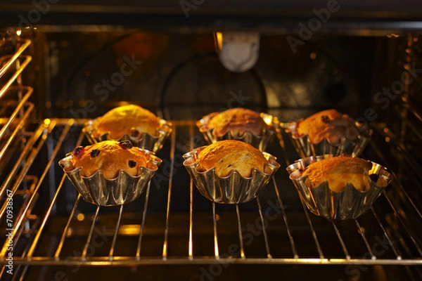 Fototapeta Baking cupcakes with raisins in baskets are baked in the oven