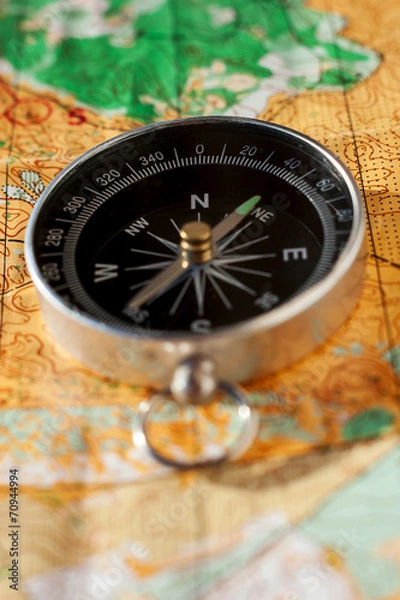 Obraz Compass laying on an orienteering map
