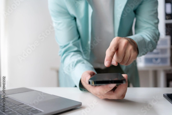 Fototapeta Close up of hands man hand using smartphone typing, chatting conversation in chat box. Man hands using smartphone in office, messaging or browsing social networks.
