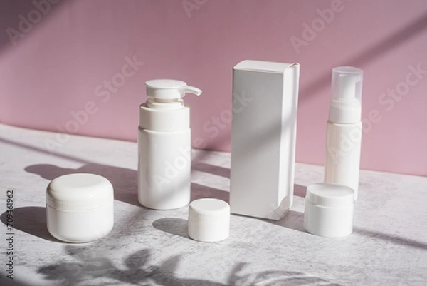 Fototapeta The white skincare set with pump, jar, and box and container on pink background.