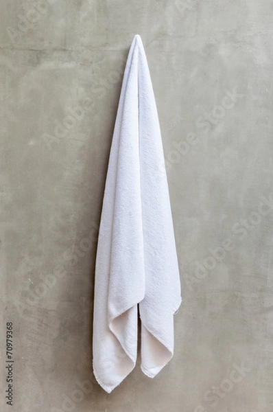 Fototapeta The white towel is hanging on a hanger with concrete wall in the