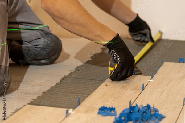 Fototapeta Repair and construction. Laying ceramic tiles using cement on the floor close-up. A man lays slabs on the floor and walls.