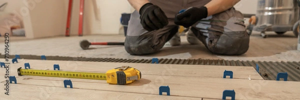 Fototapeta Repair and construction. Laying ceramic tiles using cement on the floor close-up. A man lays slabs on the floor and walls.
