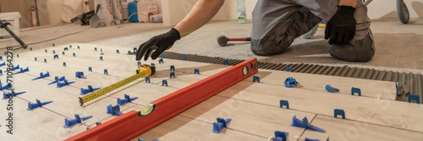 Fototapeta Repair and construction. Laying ceramic tiles using cement on the floor close-up. A man lays slabs on the floor and walls.