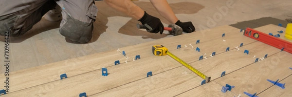 Fototapeta Repair and construction. Laying ceramic tiles using cement on the floor close-up. A man lays slabs on the floor and walls.
