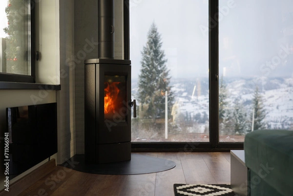 Fototapeta Modern fireplace and glass heater in a cozy house with mountain view