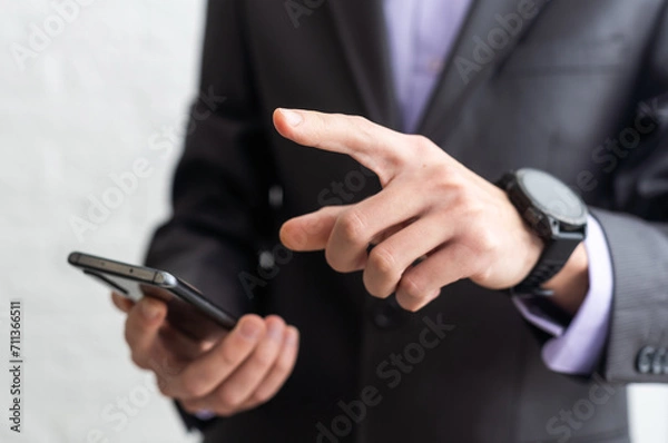 Fototapeta Businessman in the suit is using smartphone