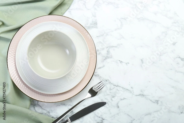 Obraz Clean plates, bowl and cutlery on white marble table, flat lay. Space for text