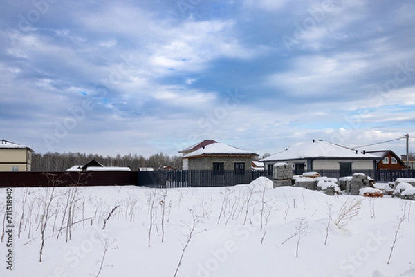Fototapeta building materials in winter on the site of future construction in the village