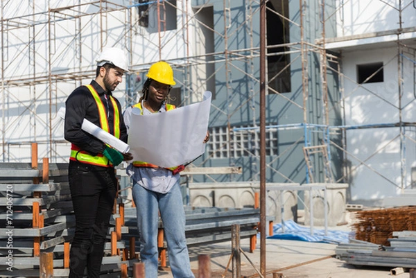 Fototapeta Construction civil engineer man and woman African American checking quality of work in construction site. Team of various nationalities working inspecting infrastructure building progress.