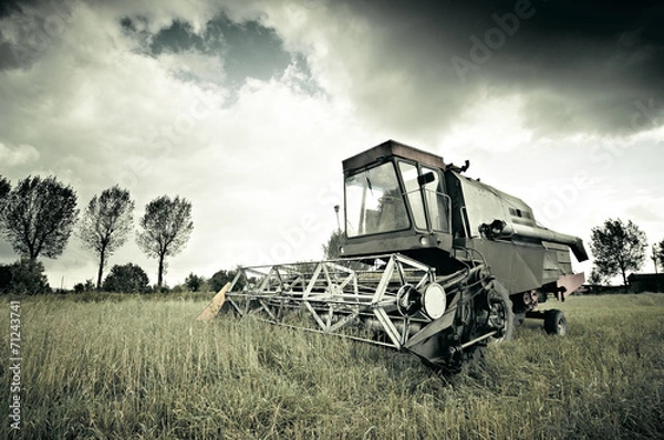 Fototapeta Old broken combine abandoned in the field during work