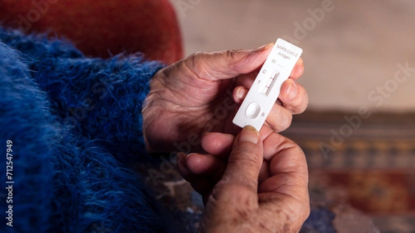 Fototapeta Close-up of grandma hand holding a positive buffer dropper of coronavirus