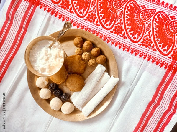 Obraz Assamese traditional food items like pitha, laddu, doi sira with assamese gamosa background with japi motifs