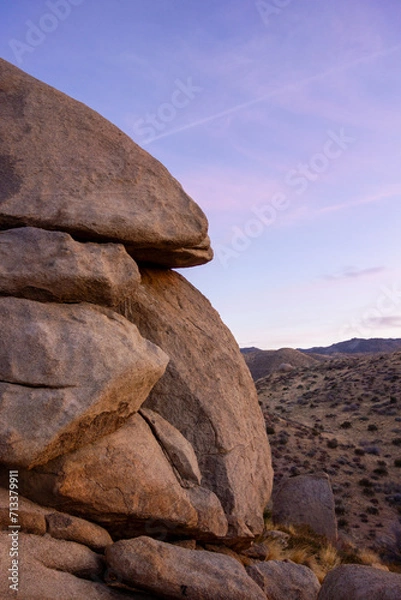 Fototapeta Sun setting behind the Mojave Desert hills and boulders in Apple Valley, CA