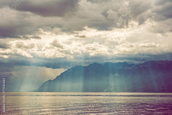 Fototapeta Sun rays falling through heavy clouds on the mountains