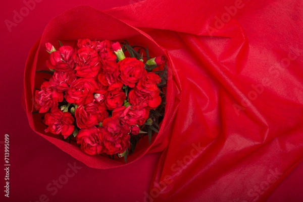 Obraz 上からの赤い背景の赤いカーネーションの花束