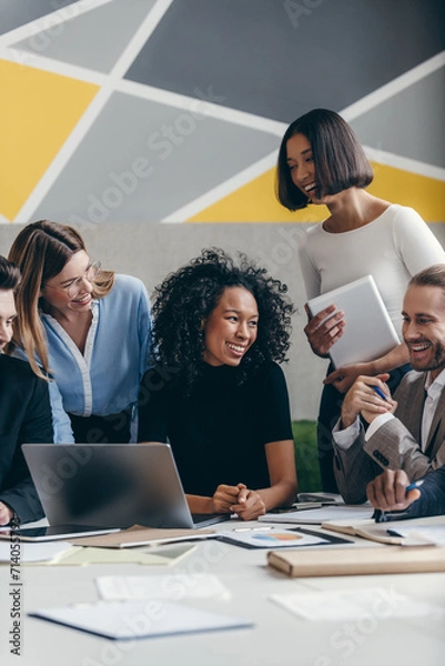 Obraz Happy young business team looking at laptop while having group meeting in the office together