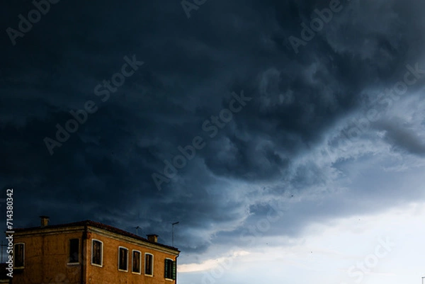 Fototapeta Dark textured and voluminous clouds before rain. Dark clouds and building