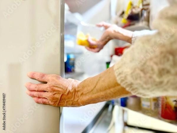 Fototapeta 冷蔵庫から食品のケースを取り出す高齢女性の手