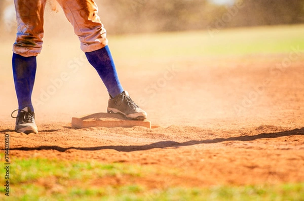 Obraz Baseball player on third base. Baseball player wearing blue socks standing on a base