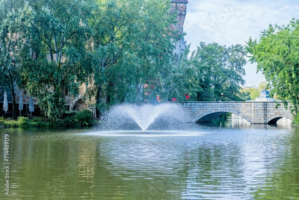 Fototapeta Water fountain in lake with bridge in background in Budapest, Hungary.