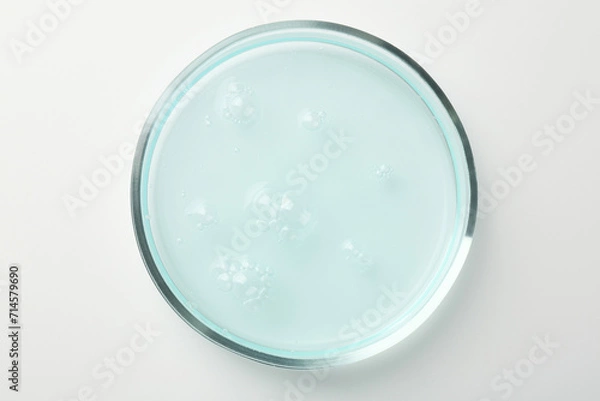 Obraz Petri dish with light blue liquid sample on white background, top view