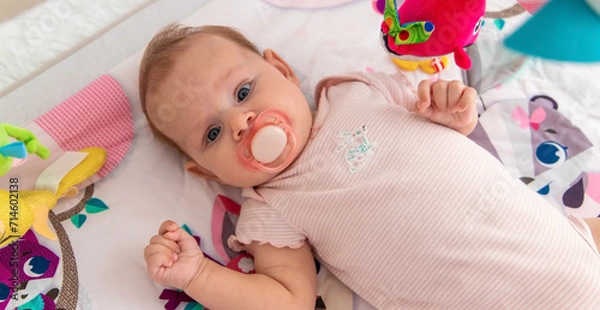 Fototapeta a baby plays with hanging toys on a play mat. a child, a baby plays at home