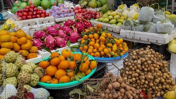 Fototapeta Colorful assortment of exotic fruits displayed at a tropical market, including dragon fruit, mangoes, and oranges