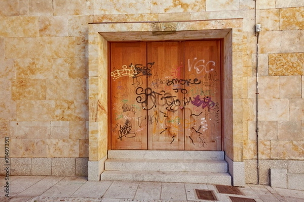 Obraz porte en fer rouillée sur façade de pierre avec graffitis