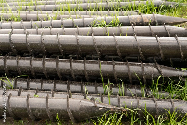 Fototapeta Screw piles for terrace foundations. Geo screws are steel round elements of an engineering structure. Industrial maintenance of metal tools for architectural construction work.