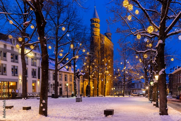 Fototapeta Maastricht, Netherlands 01-19-2024 Basilica of Our Lady and the square during twilight, covered with fresh snow during winter time and illuminated with Christmas decoration, creating a magical scene 