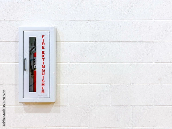 Fototapeta Red fire extinguisher in fireproof metal box installed isolated on the brick wall, law and regulations of safety for buildings, inside residential and commercial areas. Emergency tools prevent damage.