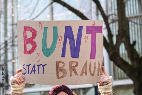 Fototapeta Woman holding a cardboard sign with the German text Bunt statt Braun (Colorful instead of Brown), as protest against racism and neo-Nazi fascism on a demonstration in Lubeck Germany, January 22, 2024