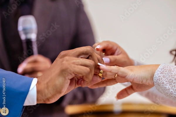 Obraz a wedding couple holding hands putting on rings