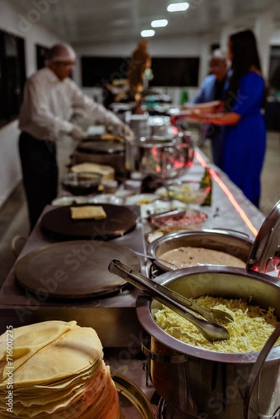 Obraz a waiter preparing crepes at a buffet table