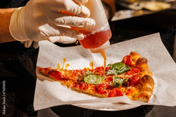 Obraz Drizzling hot honey on a pizza slice