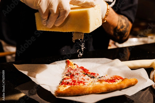 Obraz Shaving fresh cheese on a pizza slice