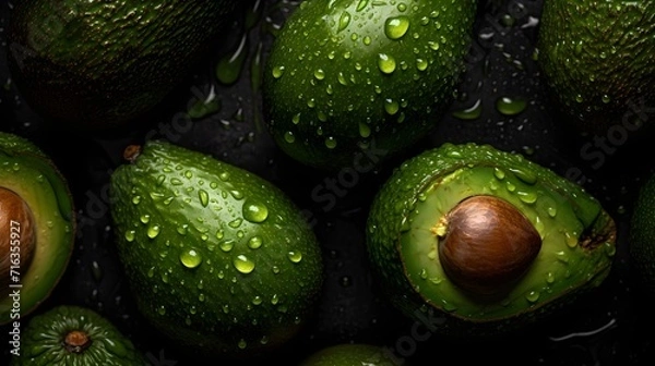 Fototapeta Fresh avocados with water splashes and drops on black background