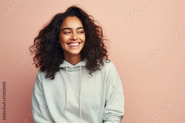 Fototapeta Portrait of a smiling woman in her 20s sporting a comfortable hoodie against a pastel or soft colors background. AI Generation