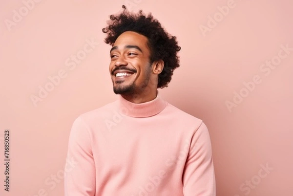 Fototapeta Portrait of a joyful indian man in his 20s wearing a classic turtleneck sweater against a solid pastel color wall. AI Generation