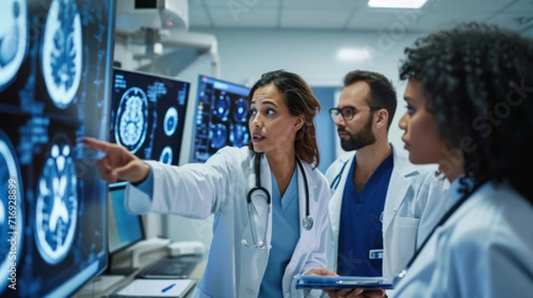Obraz Group of medical professionals is intently examining a series of brain MRI scans displayed on a lightbox in a hospital or clinic setting.