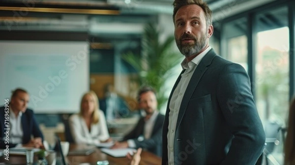Fototapeta Group of diverse businesspeople discussing paperwork together during a meeting around a table in a modern office